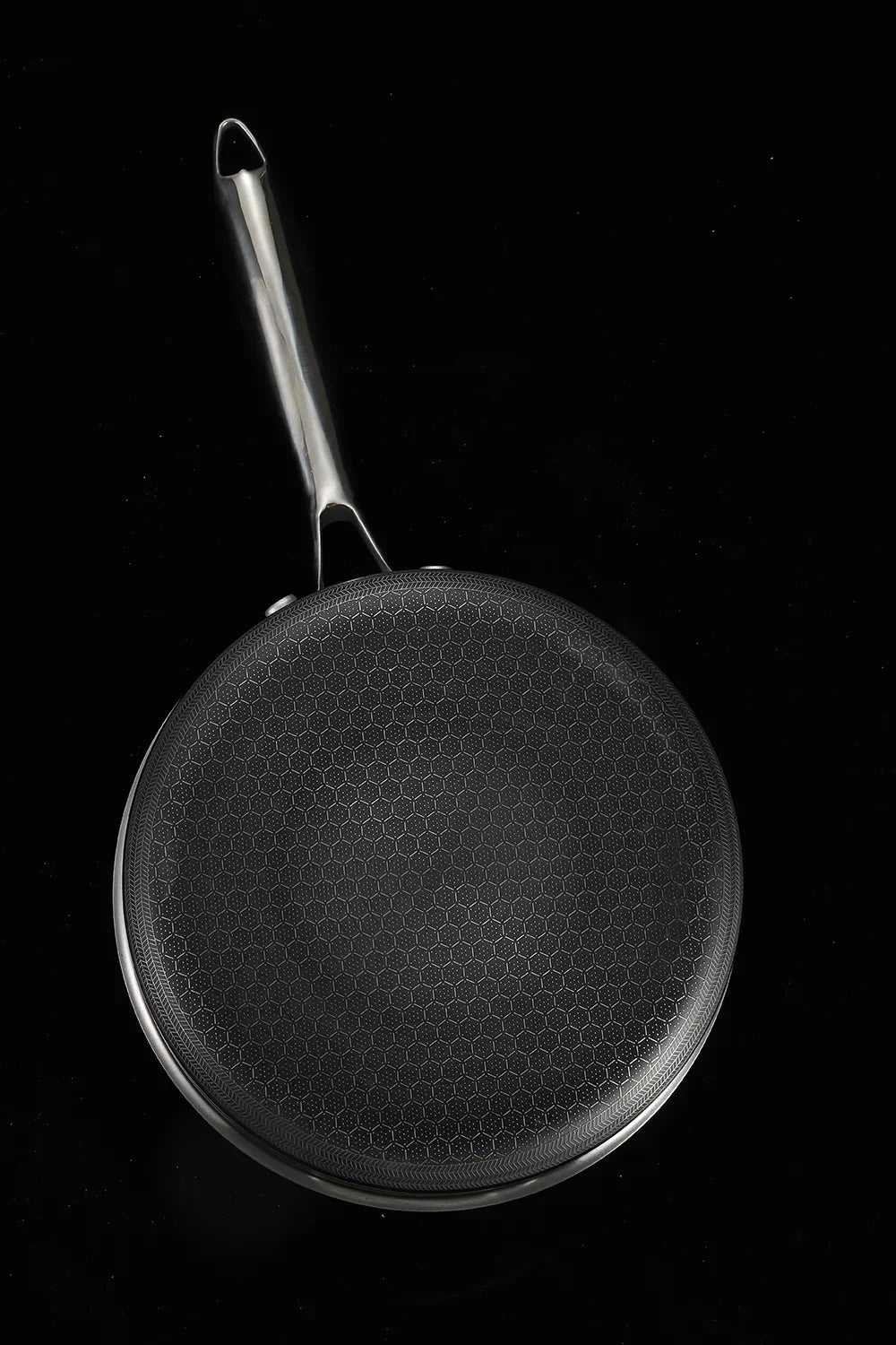 Black frying pan with a textured surface on a black background